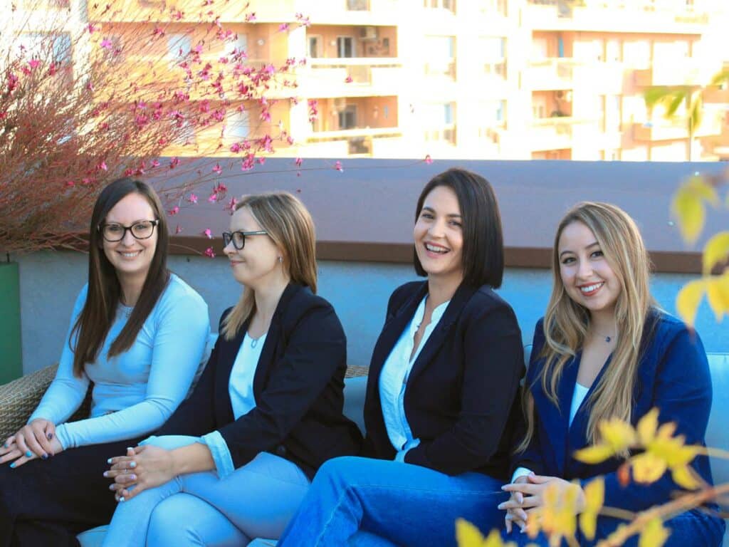Cuatro asesoras comerciales de Formintegral sentadas en una terraza, sonriendo en un ambiente relajado y profesional.