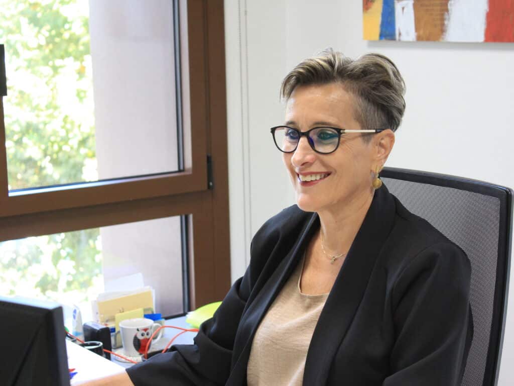 Profesional de Formintegral sonriendo mientras trabaja en su oficina, en un entorno luminoso y moderno